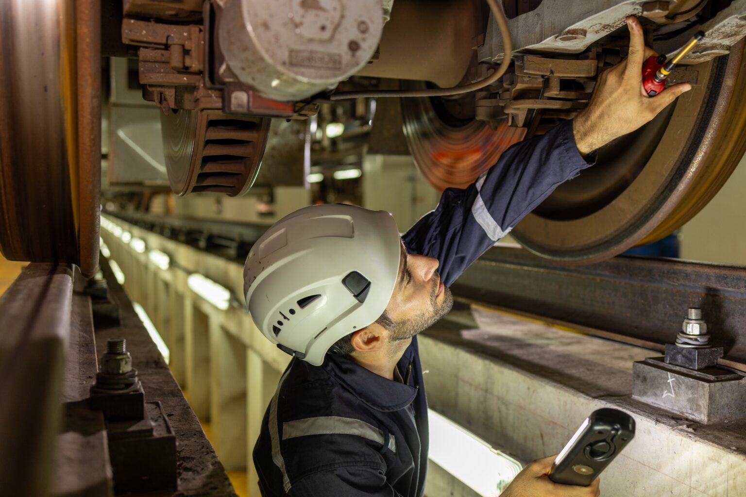 Field technician inspecting a rail vehicle underframe
